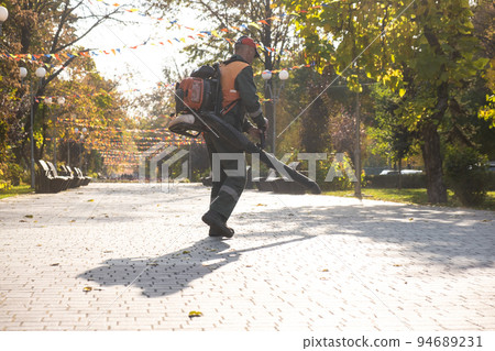 Blower cleaning from pavement leaves. Blower cleaning from pavement leaves. 94689231