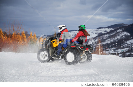 Portrait of man and woman riding on offroad four-wheeler ATV. Concept of active leisure and winter activities. 94689406