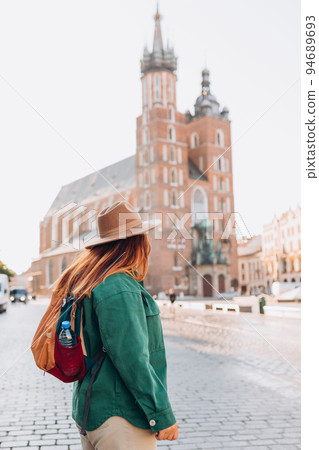 Famous cathedral in sun light, Tourist happy woman on Market Square in Krakow, Traveling Europe in autumn. St. Marys Basilica 94689693