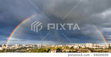 A large rainbow in the cloudy sky over the city after heavy rain. 94689899