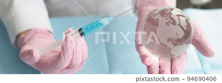 Medical worker hold syringe and miniature world globe in hands Medical worker hold syringe and miniature world globe in hands 94690406