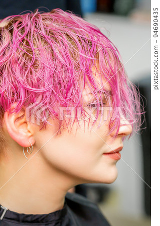 Beautiful young caucasian woman receiving new short pink hairstyle in hairdresser salon Beautiful young caucasian woman receiving new short pink hairstyle in hairdresser salon 94690435