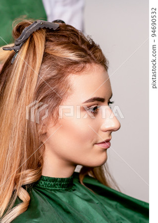 Professional hair care. Beautiful young caucasian blonde woman with long hair receiving hairstyling in a beauty salon Professional hair care. Beautiful young caucasian blonde woman with long hair receiving hairstyling in a beauty salon 94690532