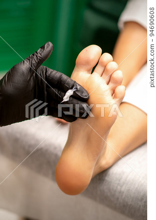 Manicure master applying cream on female client foot massage in a beauty salon Manicure master applying cream on female client foot massage in a beauty salon 94690608