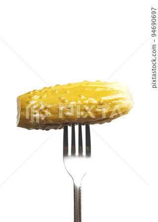 Marinated cornichon on the fork isolated on the white background Marinated cornichon on the fork isolated on the white background 94690697