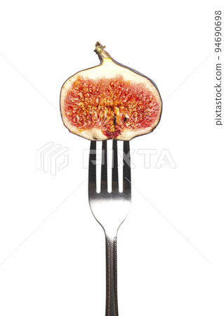 Dark fig on a fork isolated on a white background Dark fig on a fork isolated on a white background 94690698