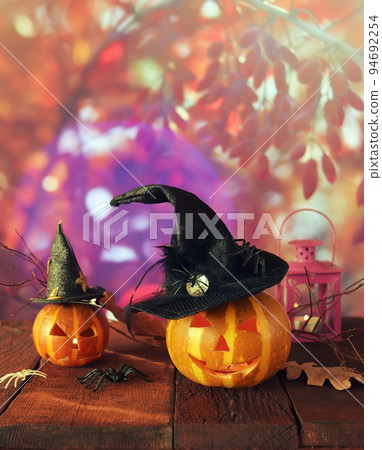 Halloween decorations, Jack-o-lantern pumpkins and a lamp with a burning candle, Halloween celebration, autumn leaves, nature background, evening, festive atmosphere, mystical and magical Halloween decorations, Jack-o-lantern pumpkins and a lamp with a burning candle, Halloween celebration, autumn leaves, nature background, evening, festive atmosphere, mystical and magical 94692254