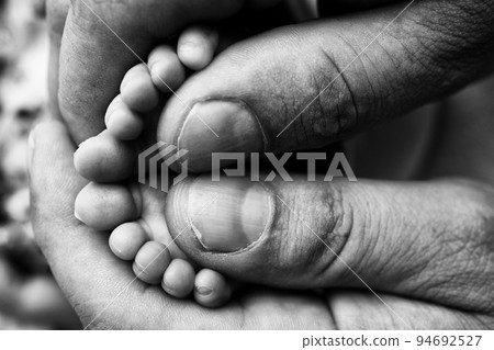 Mother is doing massage on her baby foot. Closeup baby feet in mother hands. Prevention of flat feet, development, muscle tone, dysplasia. Family, love, care, and health concepts. Black and white . Mother is doing massage on her baby foot. Closeup baby feet in mother hands. Prevention of flat feet, development, muscle tone, dysplasia. Family, love, care, and health concepts. Black and white . 94692527