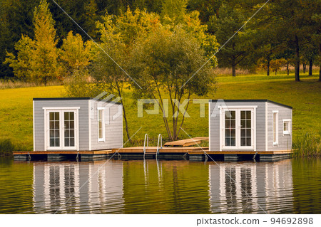 Couple of floating cabins with nice reflection on the lake water 94692898