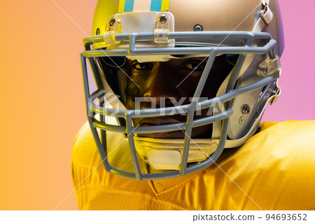 African american male american football player wearing helmet with neon yellow and purple lighting 94693652