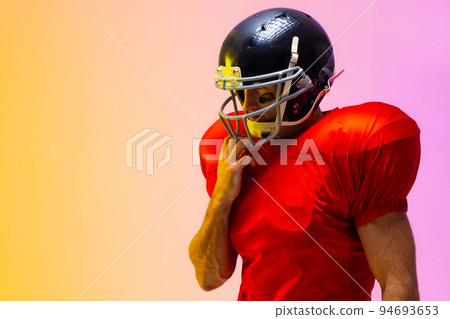 Caucasian male american football player wearing helmet with neon yellow and purple lighting 94693653