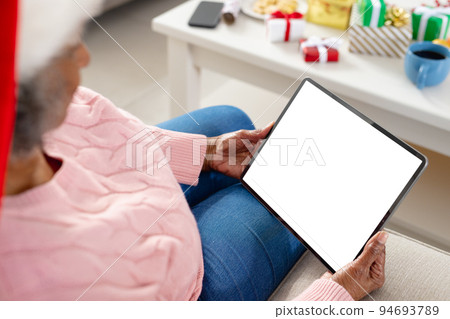 Happy senior african american women wearing santa claus hat and holding tablet with copy space 94693789