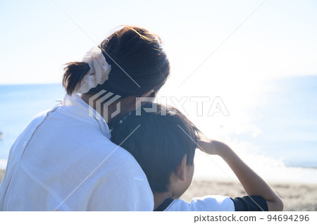 Rear view of parent and child looking at the sea Rear view of parent and child looking at the sea 94694296