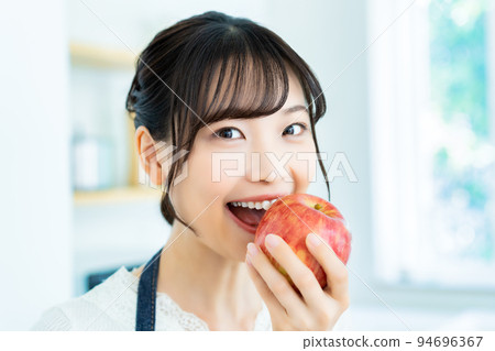 在廚房裡吃蘋果的年輕女人 94696367