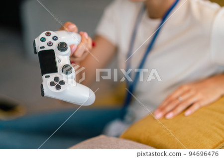Young woman with a game pad in hand playing online game 94696476