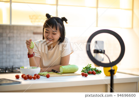 Cheerful cooking vlogger live-streaming her video blog to followers 94696600