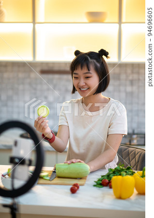 Joyous housewife shooting a cooking video for her audience Joyous housewife shooting a cooking video for her audience 94696605