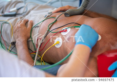 Experienced paramedic listening to the adult man heartbeat with the stethoscope 94697475