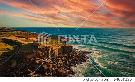 Beautiful natural landscape with ocean rocky shore during sunset with purple cloudy sky. Drone view to the rocky coast at Santu Isidoro. Aerial view over Scenic ocean scape with sunset clouds on sky. Beautiful natural landscape with ocean rocky shore during sunset with purple cloudy sky. Drone view to the rocky coast at Santu Isidoro. Aerial view over Scenic ocean scape with sunset clouds on sky. 94698150