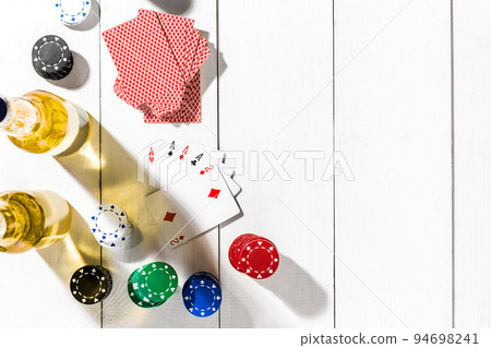 Four aces surrounded by poker chips and beer on white wooden background and copy space Four aces surrounded by poker chips and beer on white wooden background and copy space 94698241
