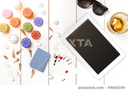 Gambling. Poker chips, cards and the dice nearby tablet on wooden table. Top view. Copyspace. Poker Gambling. Poker chips, cards and the dice nearby tablet on wooden table. Top view. Copyspace. Poker 94698394