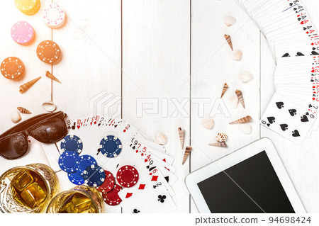 Gambling. Poker chips, cards and the dice nearby tablet on wooden table. Top view. Copyspace. Poker 94698424