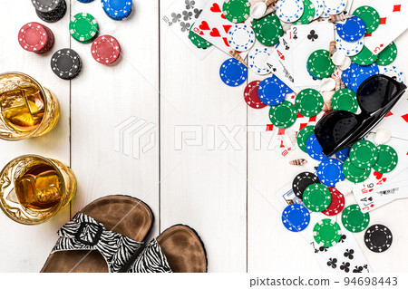 Card deck surrounded by poker chips and scattered seashells on white wooden background with copy space 94698443