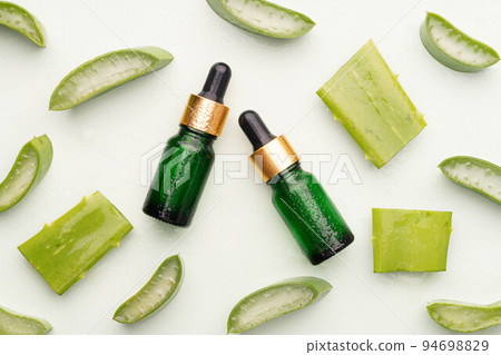 Natural moisturizer skincare product with fresh aloe vera on green background. Serum or essential oils with organic herbal extract in glass bottle for healthy skin. Dermatology and medicine concept. 94698829