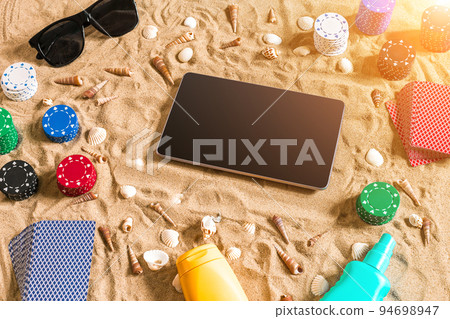 Gambling on vacation concept - white sand with seashells , colored poker chips and cards. Top view 94698947