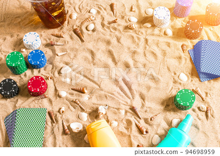 Gambling on vacation concept - white sand with seashells , colored poker chips and cards. Top view 94698959