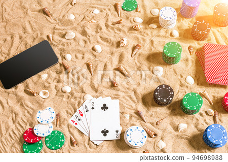 Online poker game on the beach with digital smart and stacks of chips. Top view 94698988
