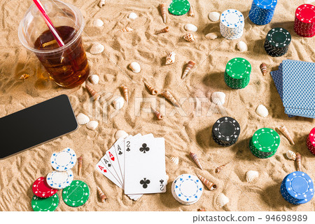Gambling on vacation concept - white sand with seashells , colored poker chips and cards. Top view 94698989