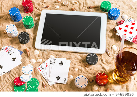 Gambling on vacation concept - white sand with seashells , colored poker chips and cards. Top view 94699056