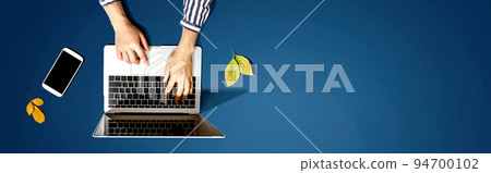 Autumn leaves with person using a laptop computer Autumn leaves with person using a laptop computer 94700102