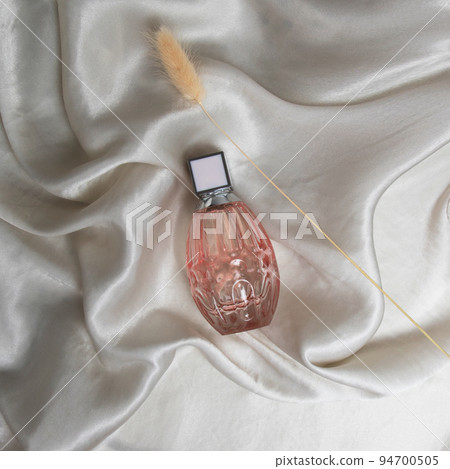 A bottle of perfume in pink glass on a background A bottle of perfume in pink glass on a background 94700505