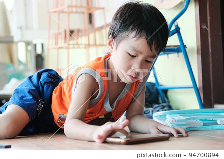 Kindergarten boy playing game in smartphone sitting in house 94700894
