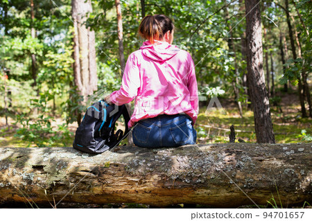 A mushroom picker girl with a backpack got lost in the forest. The girl is sitting on a tree. Survival in the forest. Location orientation. A mushroom picker girl with a backpack got lost in the forest. The girl is sitting on a tree. Survival in the forest. Location orientation. 94701657
