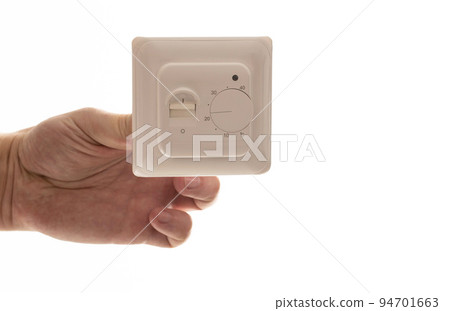 A man holds in his hand an electric thermostat for a warm floor on a white background, isolate. Close-up 94701663