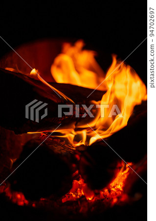 Burning firewood in the fireplace in the oven. Fire texture on black background 94702697