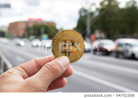 Bitcoin against the backdrop of road with cars 94702806