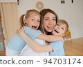 Two children son and daughter hug their mother. Happy loving family standing 94703174