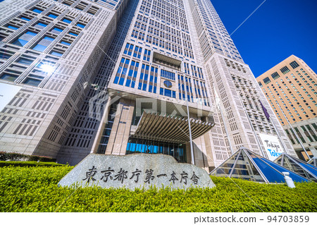 日本東京城市景觀 東京都政府大樓。東京都政府第一本館和入口前的石碑，沐浴在強烈的早晨陽光下。 94703859