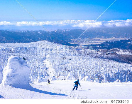 People skiing through a field of frost-covered trees at a sunny ski resort (Zao Onsen Ski Resort, Yamagata Prefecture) People skiing through a field of frost-covered trees at a sunny ski resort (Zao Onsen Ski Resort, Yamagata Prefecture) 94703943
