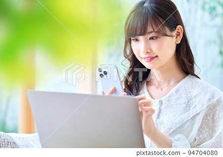 一名年輕女子在遠程辦公期間在客廳操作智能手機 94704080