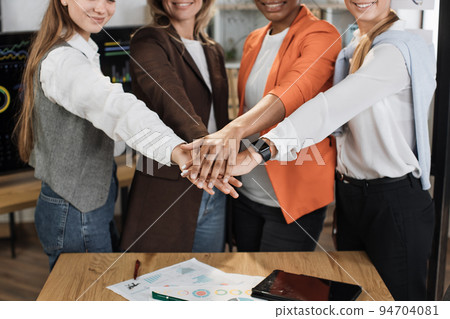 Close up of female stacking hands together after successful meeting at office room. Close up of female stacking hands together after successful meeting at office room. 94704081