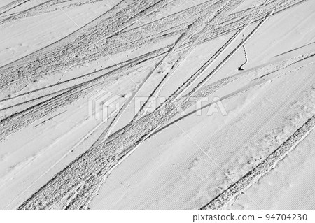 Snowy ski slope with trace from skis and snowboards at winter. Black and white. High contrast. Snowy ski slope with trace from skis and snowboards at winter. Black and white. High contrast. 94704230