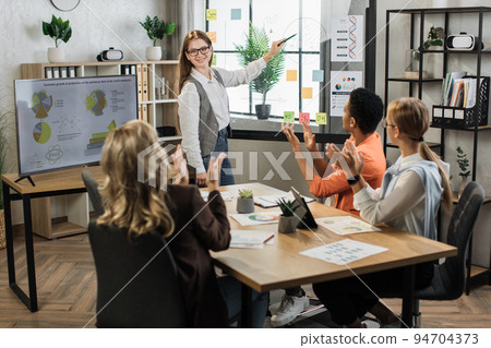 Caucasian woman in formal wear pointing on glass board with charts and graphs 94704373