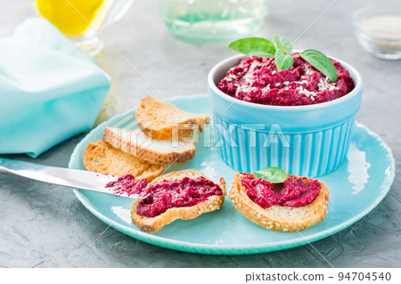 Homemade bruschetta with beetroot hummus on small toast on a plate and a table knife on the table Homemade bruschetta with beetroot hummus on small toast on a plate and a table knife on the table 94704540