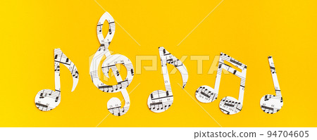 Musical notes and clef cut from paper with musical text in a row on yellow background. Web banner Musical notes and clef cut from paper with musical text in a row on yellow background. Web banner 94704605