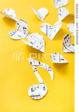 Musical notes, clef and hearts cut from paper with musical text on yellow background. Vertical view 94704606